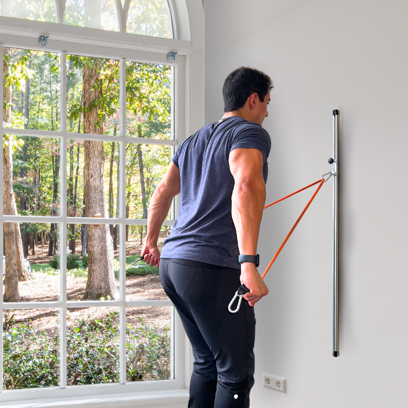 User is performing tricep extension exercise with resistance band wall mount.