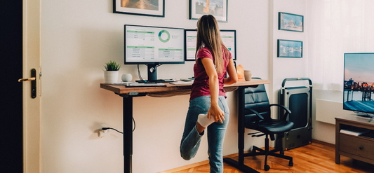 Woman working from home, stretching at a stand-up desk. 